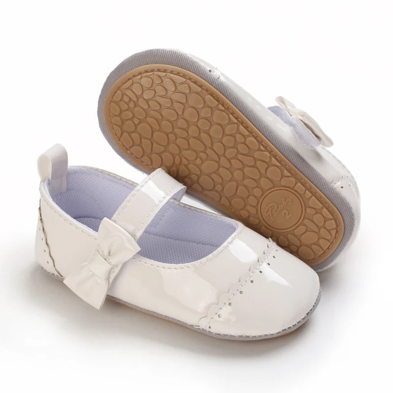 A pair of white baby first walker shoes with a light purple lining and a tan non-slip sole.