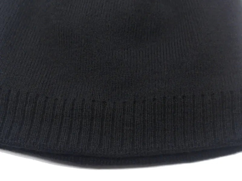 A close-up view of a black knitted beanie hat with ribbed texture.
