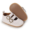 A pair of white soft non-slip baby first walker shoes with tan rubber soles.
