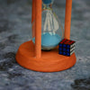 A mini 3x3 speed cube is placed on a wooden stand beneath an hourglass.