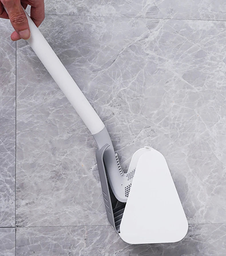 A hand is holding a white golf-style silicone toilet brush with a self-opening holder against a gray marble surface.