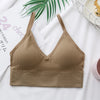 A beige seamless U-back bralette top is displayed on a white background next to a green palm leaf.