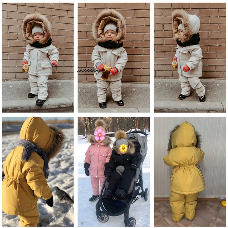 A baby wearing a yellow winter down jacket and pants set with a faux fur hood standing outdoors.