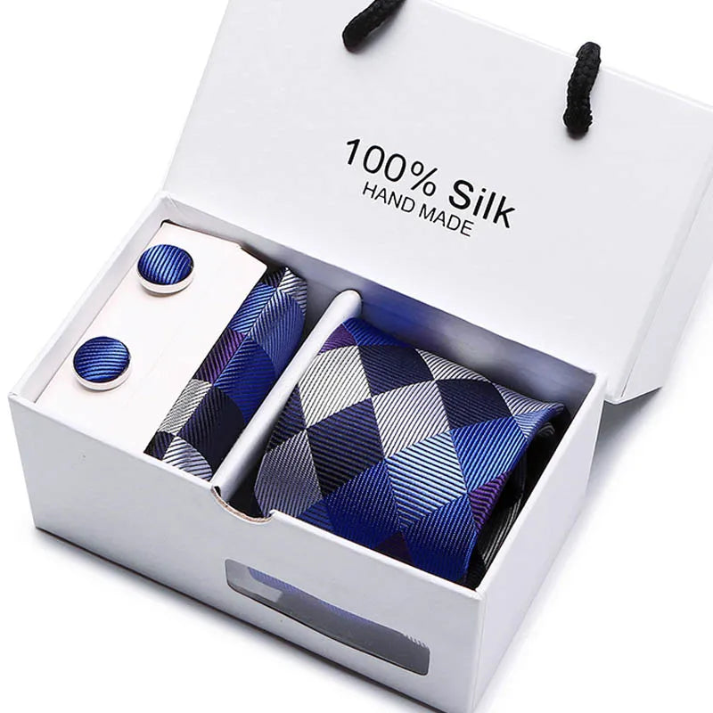 Corbata de seda azul marino con estampado jacquard y dos gemelos en una caja blanca.