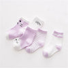 A set of five striped cotton baby socks in lavender and white colors.