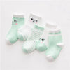 A set of light green and white striped cotton baby socks with cute face designs.