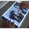 يد ترسم على لوحة رسم A4 LED بقلم ضوئي تحت ضوء ساطع.