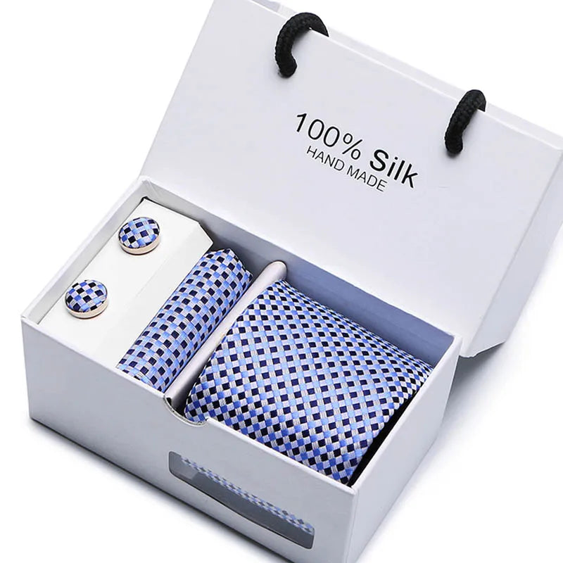Una caja blanca con una corbata de seda azul marino, jacquard, hecha a mano, con diseño de cachemira y dos botones plateados