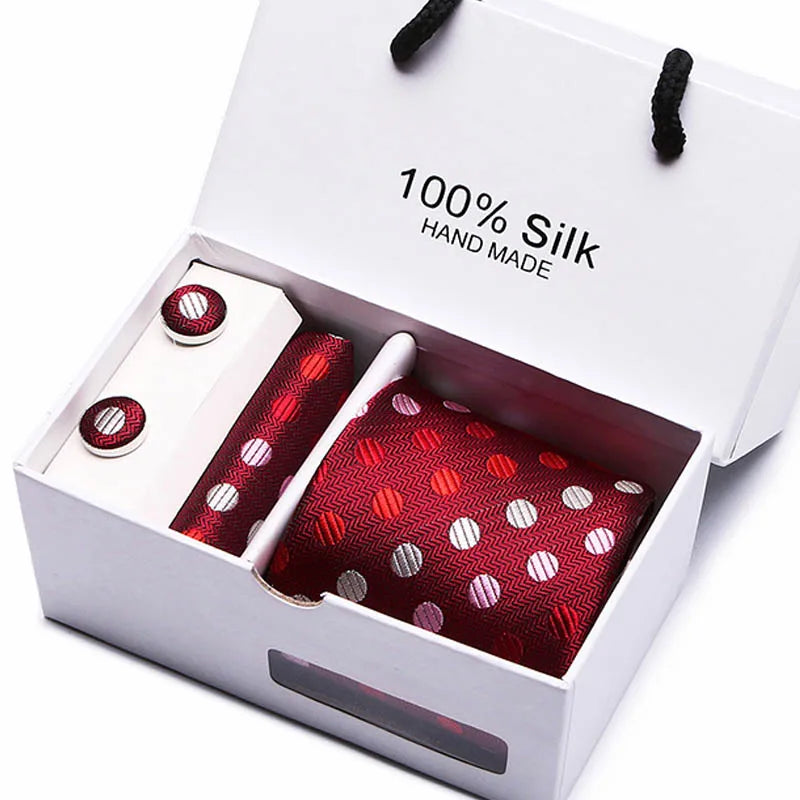 Una corbata de seda azul marino hecha a mano, con estampados paisa rojos y blancos, en una caja blanca.