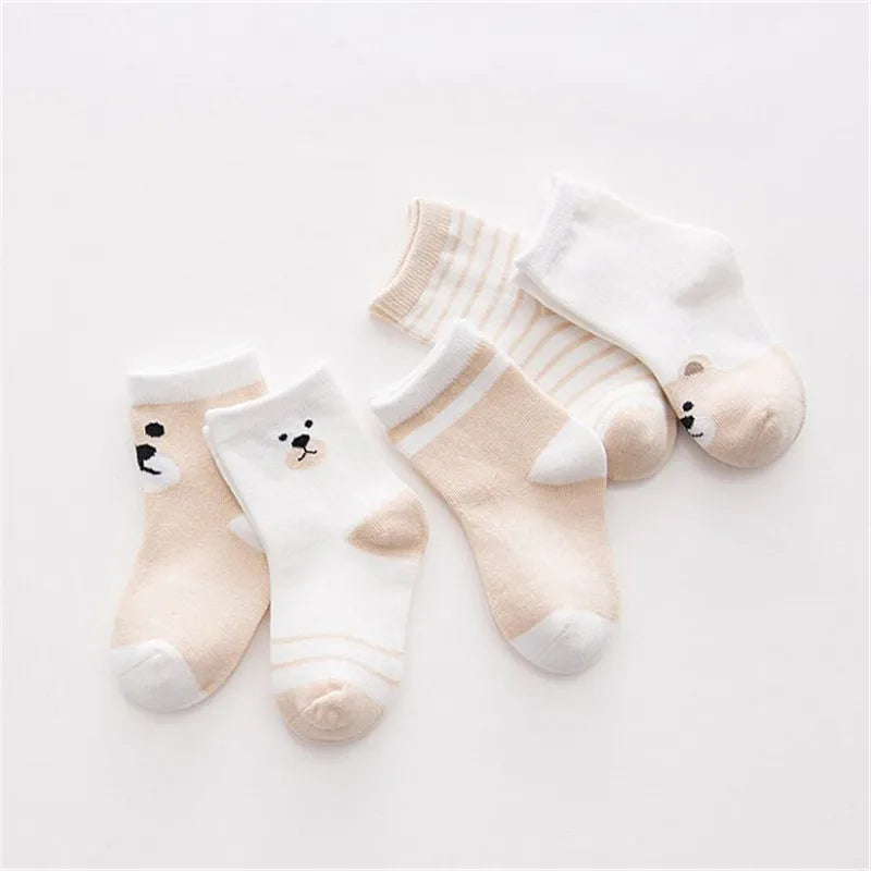 A set of five striped cotton baby socks in cream and white colors laid out on a white background.