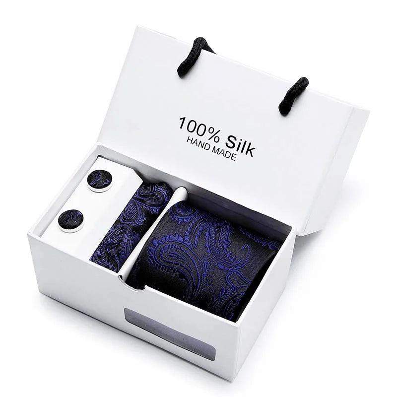 Caja con corbata de seda jacquard azul marino con estampado de cachemira, lazos negros visibles en su interior.