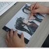 يد ترسم على لوحة رسم LED بحجم A4 بقلم ملون على طاولة خشبية.