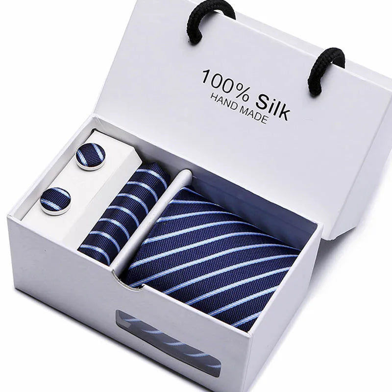 Una caja blanca con una corbata de seda azul marino, hecha a mano, estampada con cachemiras, y dos botones pequeños de seda.