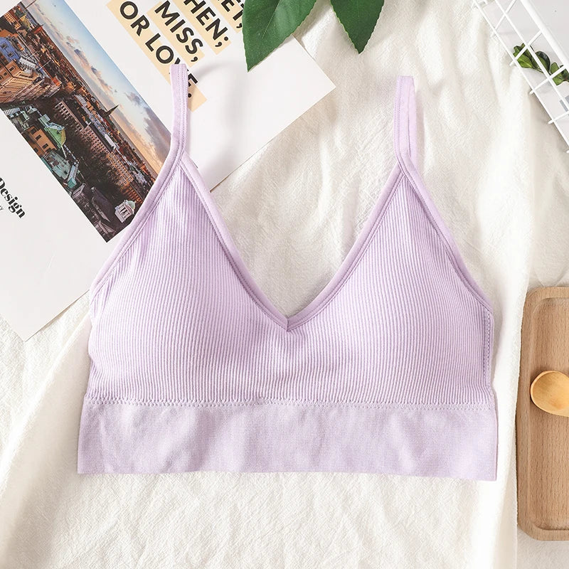 A light purple seamless U-back bralette with thin straps and removable pads displayed on a white fabric.