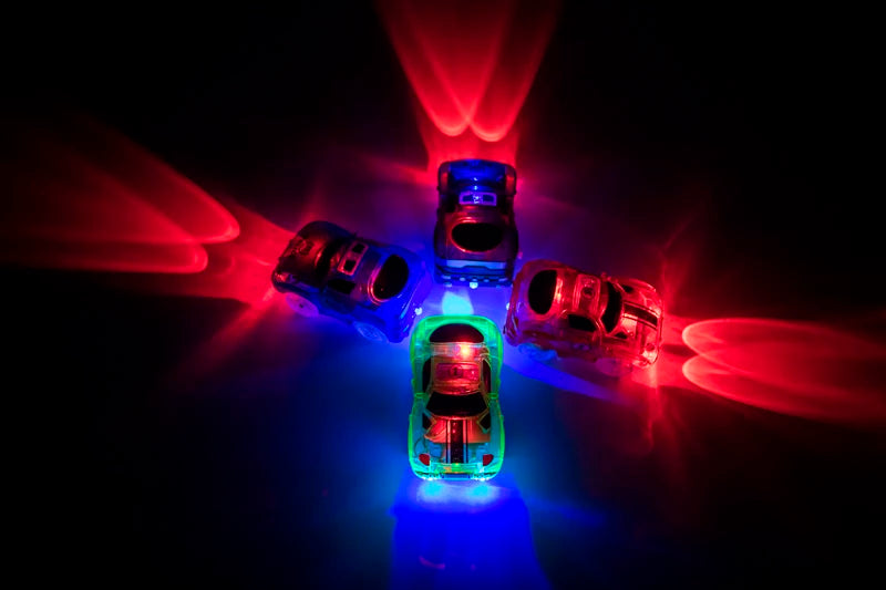 A set of glowing magnetic race track components including ramps and bridges illuminated by red and blue light.