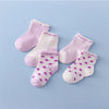 A collection of pink and white striped cotton baby socks laid out on a light blue background.