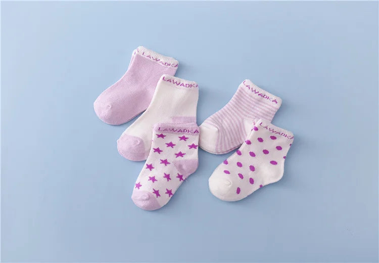A collection of pink and white striped cotton baby socks laid out on a light blue background.