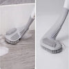 A close-up view of a gray silicone toilet brush with a self-opening holder, showing the bristles and handle.