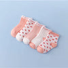 A set of pink and white striped cotton baby socks laid out on a light blue background.