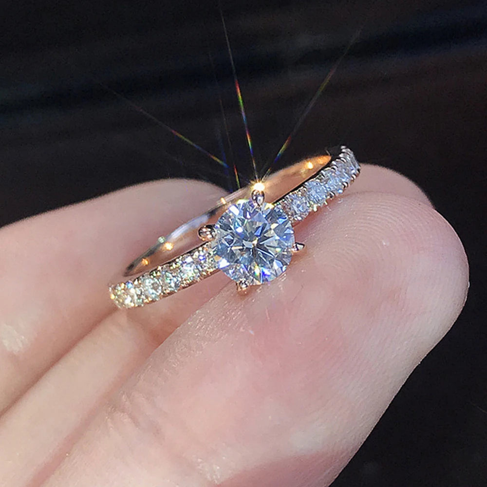 Nærbilde av en klassisk rund kubisk zirkonia-bryllupsring på en finger.