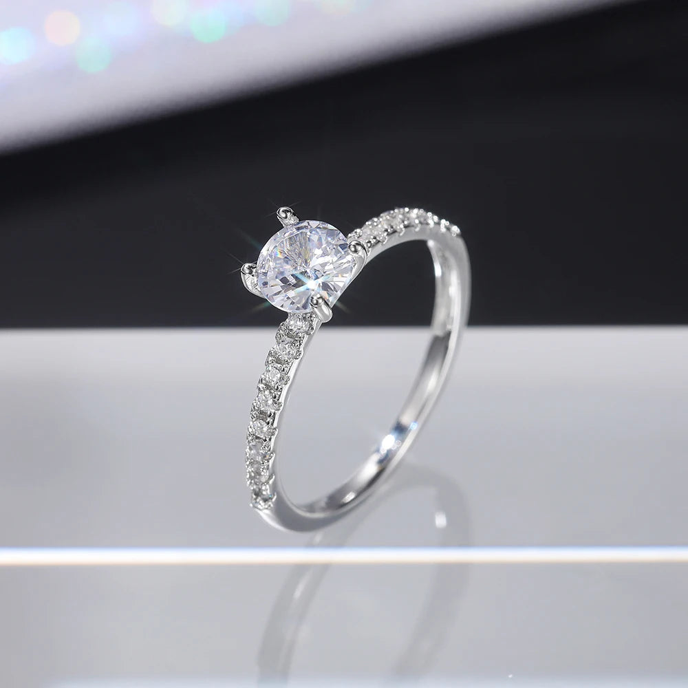Nærbilde av klassisk rund bryllupsring med cubic zirconia og pavé-diamantband på hvit overflate.