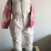 A baby winter down jacket and pants set in white with pink checkered sleeves and a faux fur hood.