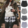 A woman wearing a plaid skirt and sweater, with an adjustable shirt extender visible.