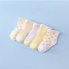 A set of five yellow and white striped cotton baby socks laid out on a light blue background.