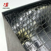 Close-up of black and gold crocodile pattern faux leather fabric for crafting