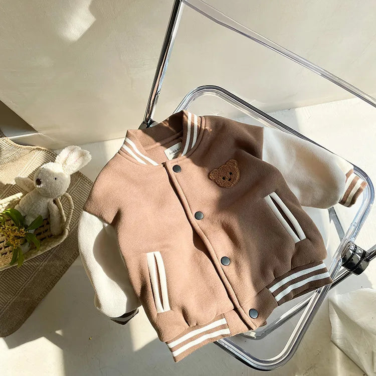 A tan fleece-lined corduroy jacket for children is displayed on a clear acrylic hanger.