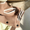 A close-up of a tan fleece-lined corduroy jacket with white stripes resting on a light beige fabric.
