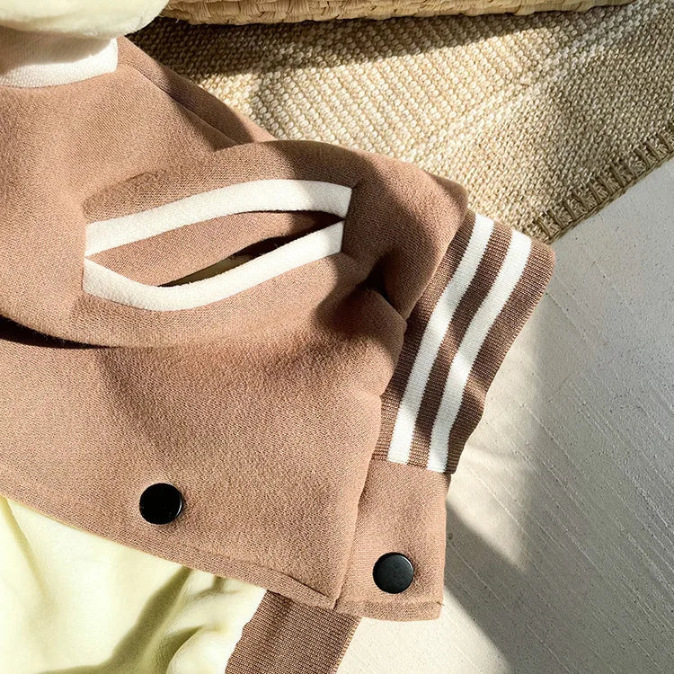 A close-up of a tan fleece-lined corduroy jacket with white stripes resting on a light beige fabric.