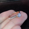 En hånd holder en klassisk rund cubic zirconia brudering med pave diamanter på ringen.