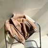 A tan fleece-lined corduroy jacket for children is displayed on a clear stand.