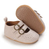 A pair of soft beige baby first walker shoes with textured soles and leather accents.