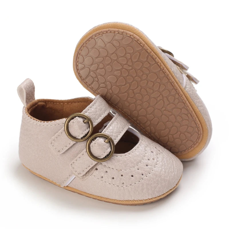 A pair of soft beige baby first walker shoes with textured soles and leather accents.