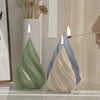 A green silicone mold shaped like a Christmas tree is shown with a lit candle, next to a gray one.