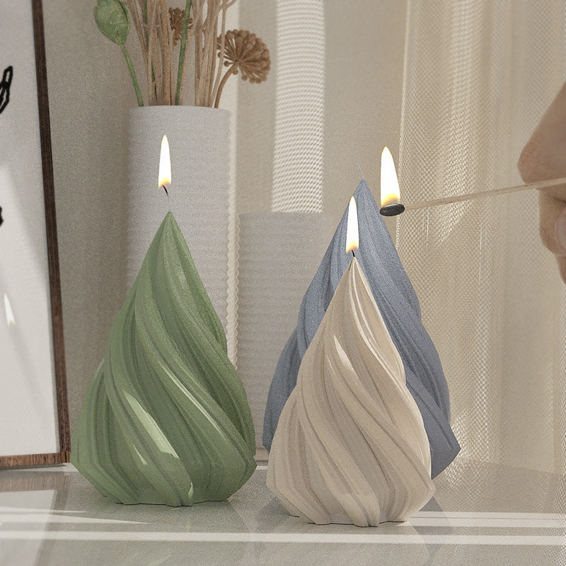 A green silicone mold shaped like a Christmas tree is shown with a lit candle, next to a gray one.