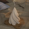 A white silicone mold shaped like a stylized Christmas tree stands on a wooden surface with smoke rising from the top.