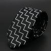 Corbata estampada de chevrones en blanco y negro enrollada sobre fondo oscuro.