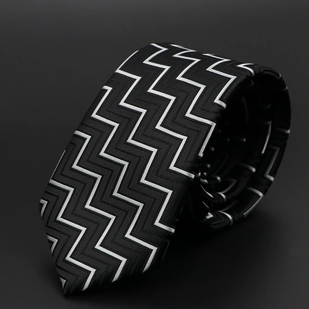 Corbata estampada de chevrones en blanco y negro enrollada sobre fondo oscuro.