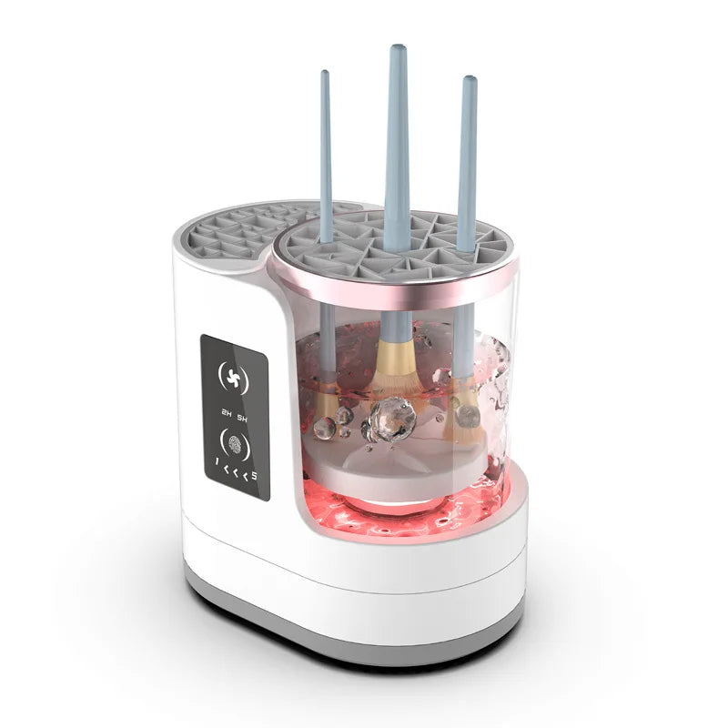 A white electric makeup brush cleaner device with a pink top section and multiple brush holders.