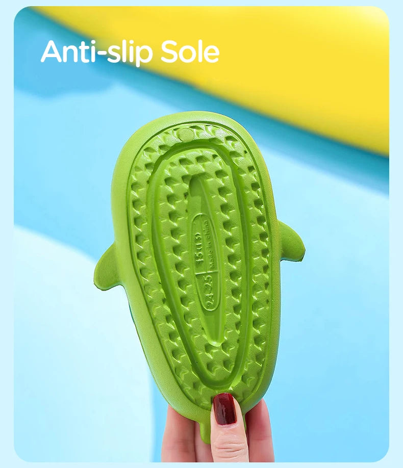 A hand holds a bright green kids shark clog sandal featuring an anti-slip sole.