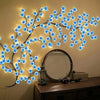 Dekorativ USB-lampa med körsbärsblomma och blå LED-lampor ovanför en byrå med spegel.