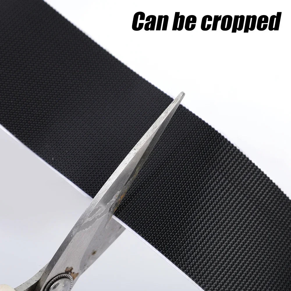 Close-up of black hook and loop fastener tape being cropped with a pair of scissors.