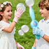 Two children are playing with a clear bubble wand and bubbles outdoors.