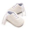 A pair of cream-colored soft sole baby pre-walker sneakers for infants, shown from the side.