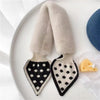 Pair of light beige faux fur toddler scarves with black cross-stitching on a white plate.