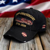 Svart basebollkeps med broderad amerikansk flagga och text om 250-årsjubileum på en träyta.