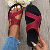 A close-up of women's breathable mesh flat sandals in maroon and gold accents being held by a hand.